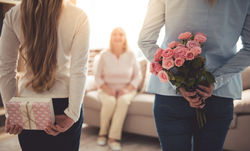 stock-photo-teenage-girl-and-her-mom-are-hiding-flowers-and-a-gift-box-for-their-beautiful-granny-behind-backs-561660988